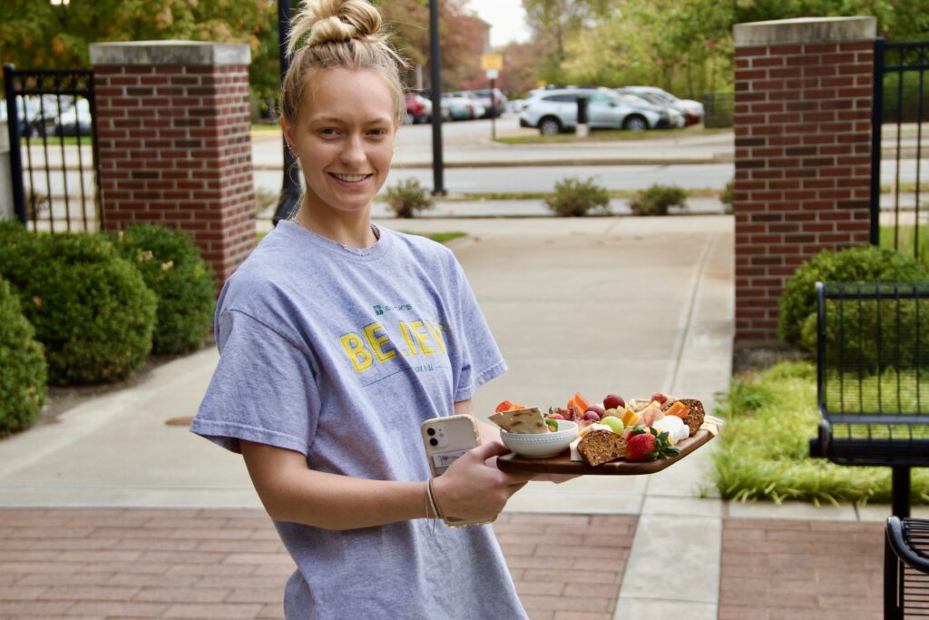 A student shows off her charcuterie board outside.