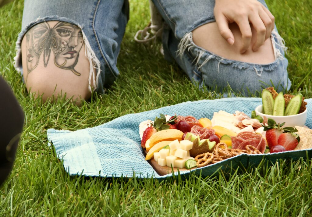 Students place a charcuterie board on the grass for a photo.