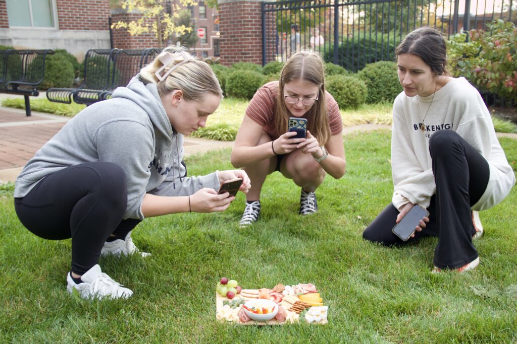Students take pictures of their charcuterie board outside.