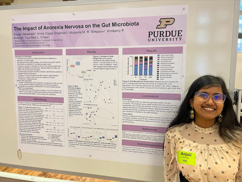 Anjali Vanamala smiles next to her research poster