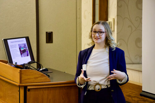 Riley Rozniarek presents her research next to a podium