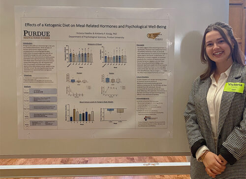 Victoria Patellos smiles next to her research poster