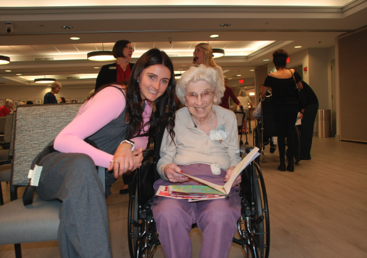 A student poses for a picture with a resident of Westminster Village.