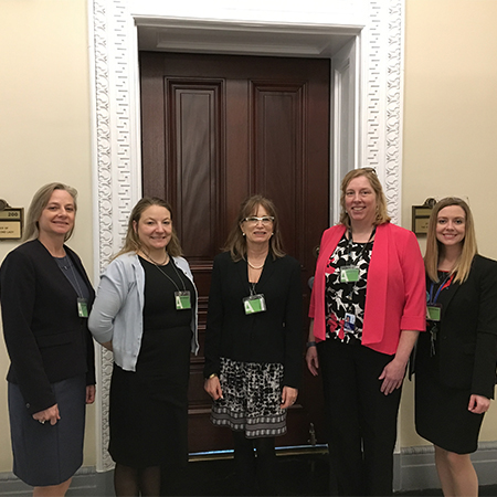 Five women pose for a photo, smiling