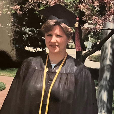 Young Janine Zweig stands in her cap and gown on Purdue's campus