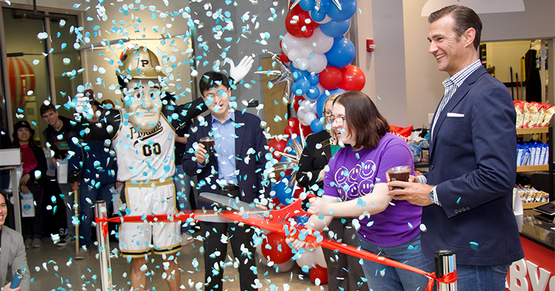 Confetti falls as a woman cuts a red ribbon with large scissors