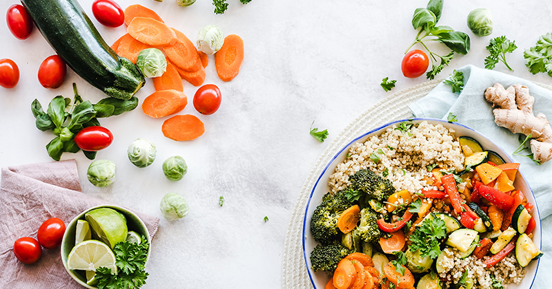 Vegetables and other healthy food items are scattered on a white tablecloth