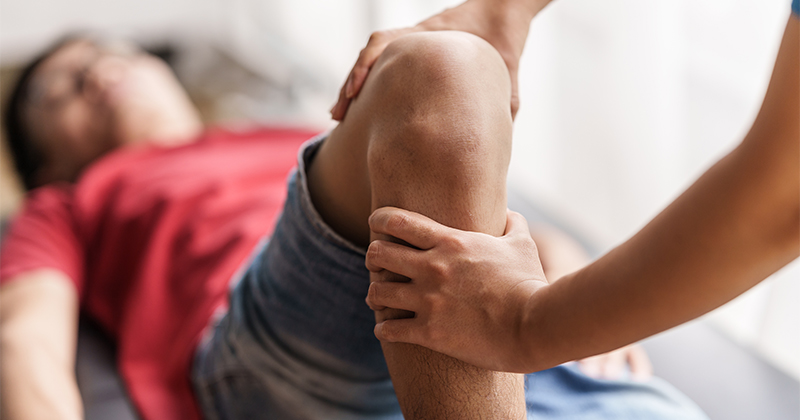 A medical professional examines a man's knee.