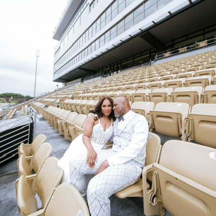 Hagins sits in stadium seats in a wedding dress with her husband.