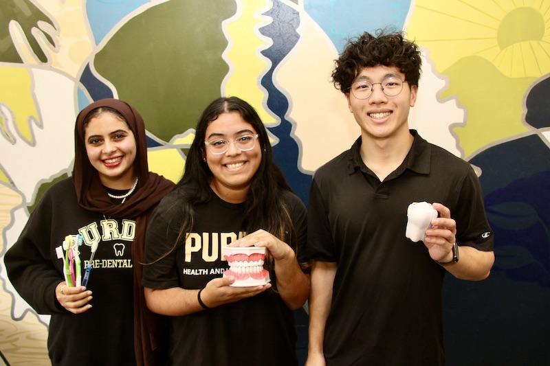 Three HHS Pre-dental students hold dentistry props while posing for a photo.