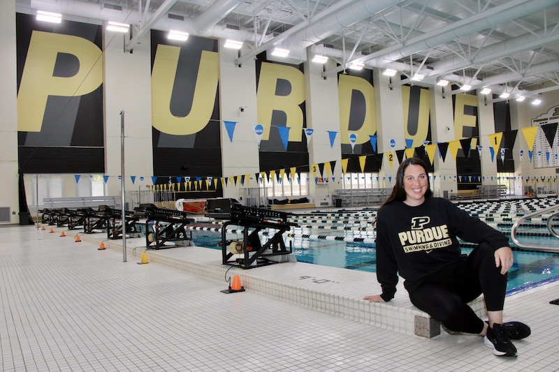 Caitlin Hamilton sits for a photo next to a swimming pool.