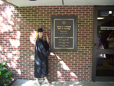 Amanda Noth-Matchett poses for a photo outside of Johnson Hall of Nursing in a cap and gown.