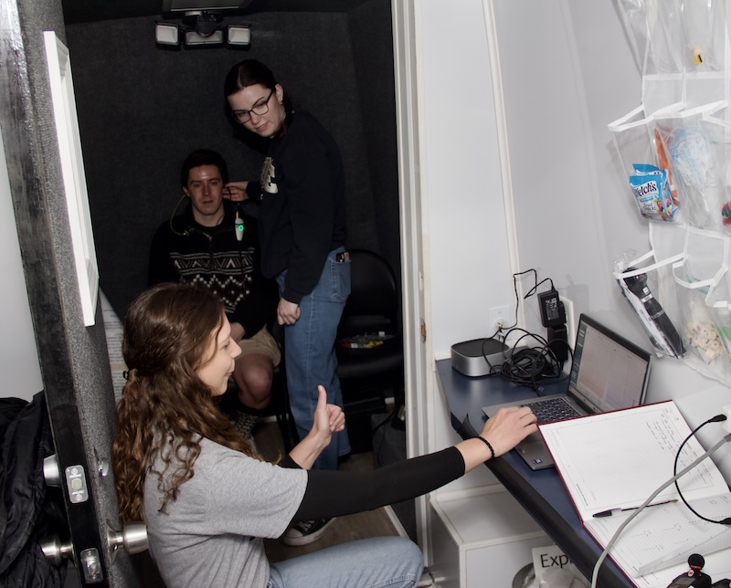 Isabella Huddleston gives a thumbs-up during a hearing test inside the APARC van.