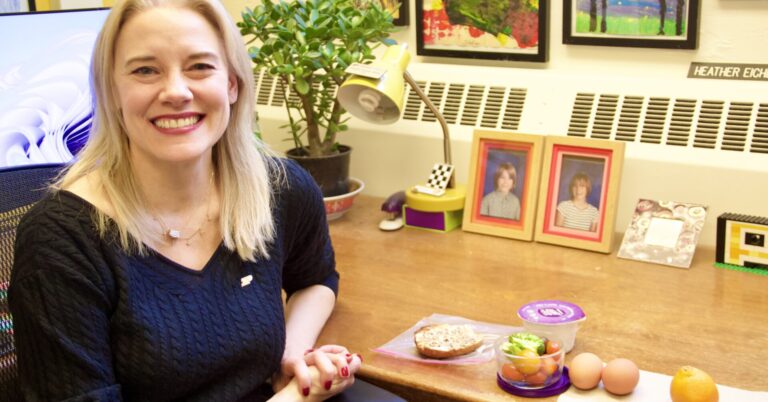 Heather Eicher-Miller sits down at her desk for lunch and smiles for a photo.