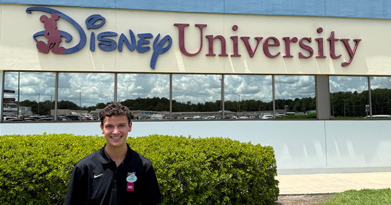 Luke Wiseman stands in front of a building with a sign that says Disney University.