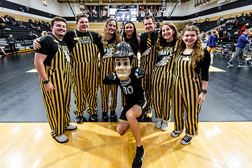 Pirbhai poses with her friends and Purdue Pete in gold and black overalls.