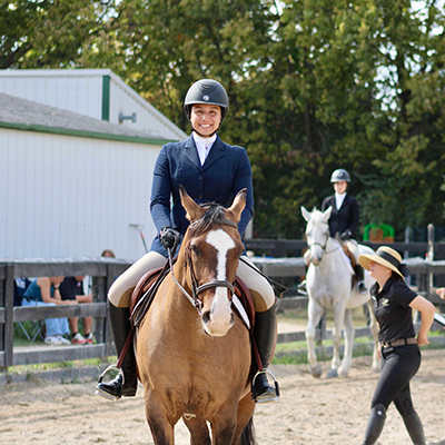 Pirbhai sits atop a horse in her equestrian uniform.