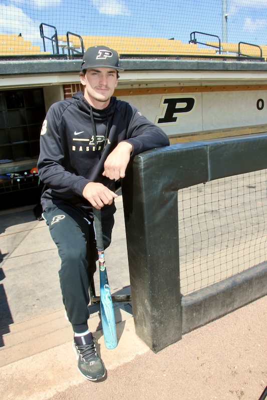 Eli Anderson holds a bat on the steps of the Purdue dugout.