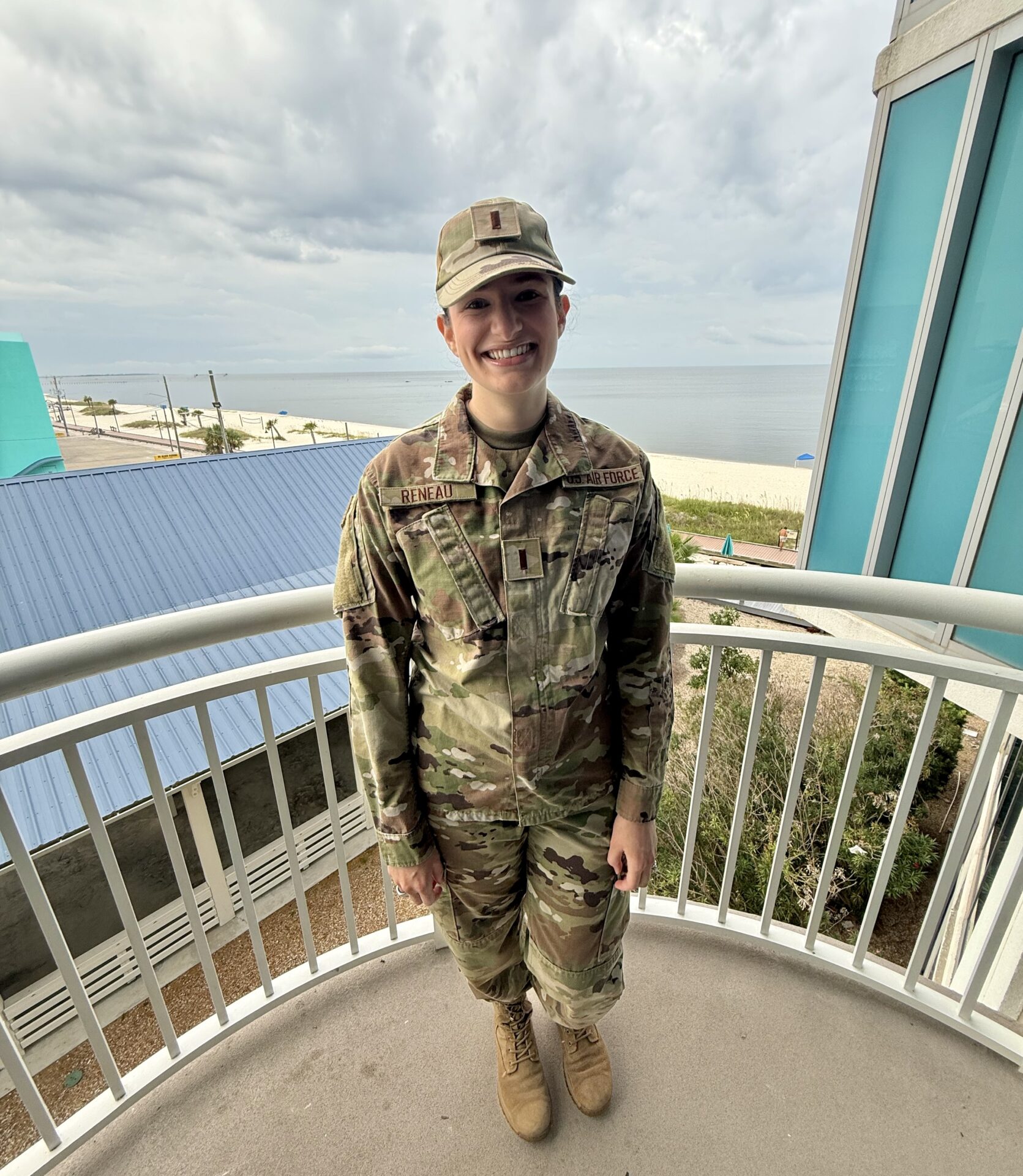 Abby Badinghaus stands on a balcony overlooking the ocean while wearing her Air Force uniform.