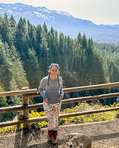 Alyssa Cutter stands in a forested area, smiling.