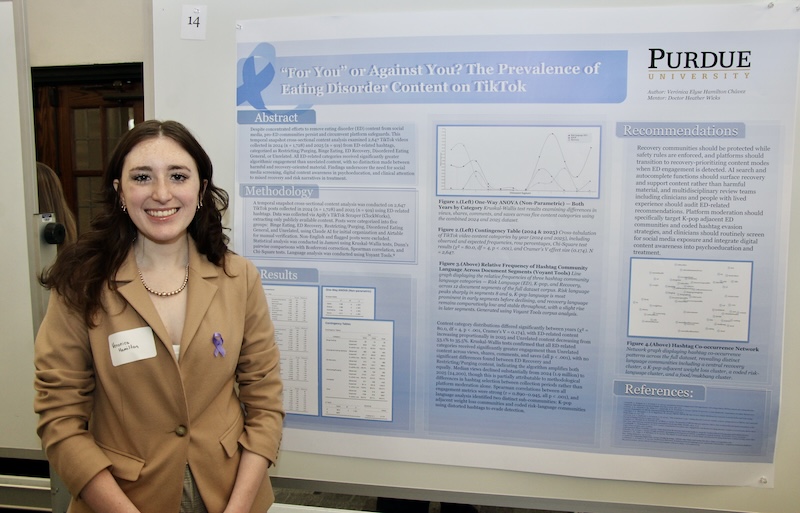 Veronica Chavez Hamilton stands smiling in front of her research poster. 