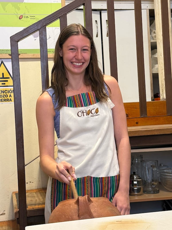 Taylor Cawood wears an apron while stirring chocolate in Peru.