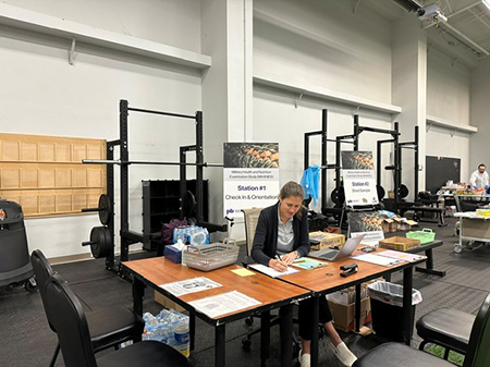 Claire Berryman sits at a desk writing on a notepad, preparing check-ins for a research study.