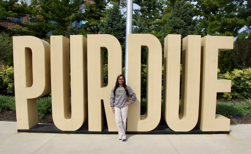 Harmony Oliver stands in front of a large Purdue side outside at the Purdue in Indianapolis location.