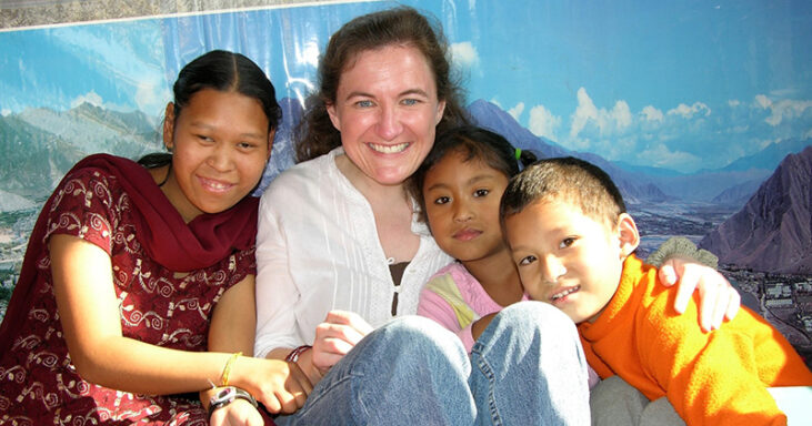 Laura smiles for a photo with children in Nepal.