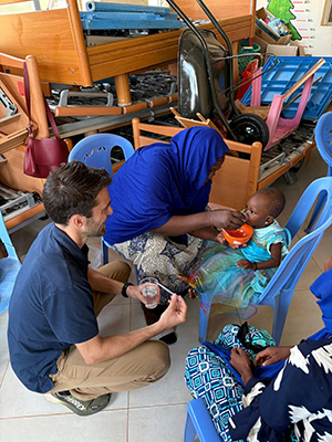 Stephen Hennigar holds a cup of water while interacting with a mother and her child during his research.