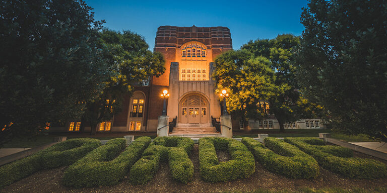 Purdue Memorial Union at night with Purdue hedge