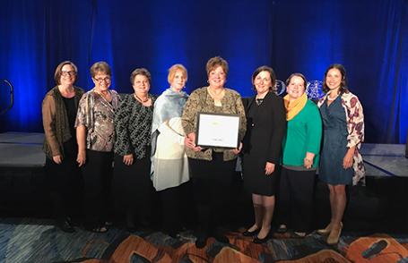 A group of Purdue School of Nursing faculty stand on stage at an awards ceremony.