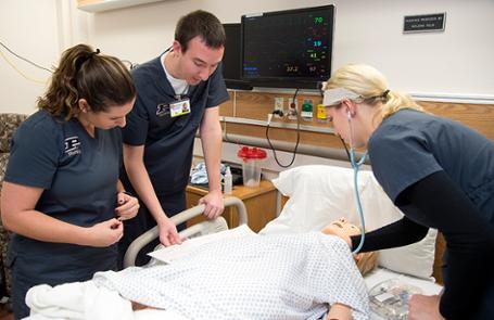 Student nurses work with a simulator manikin