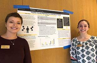 Nursing students Sierra Smith (left) and Samantha Puckett stand with a poster presentation of their Fayette County public health research. (Photo courtesy of Sierra Smith)