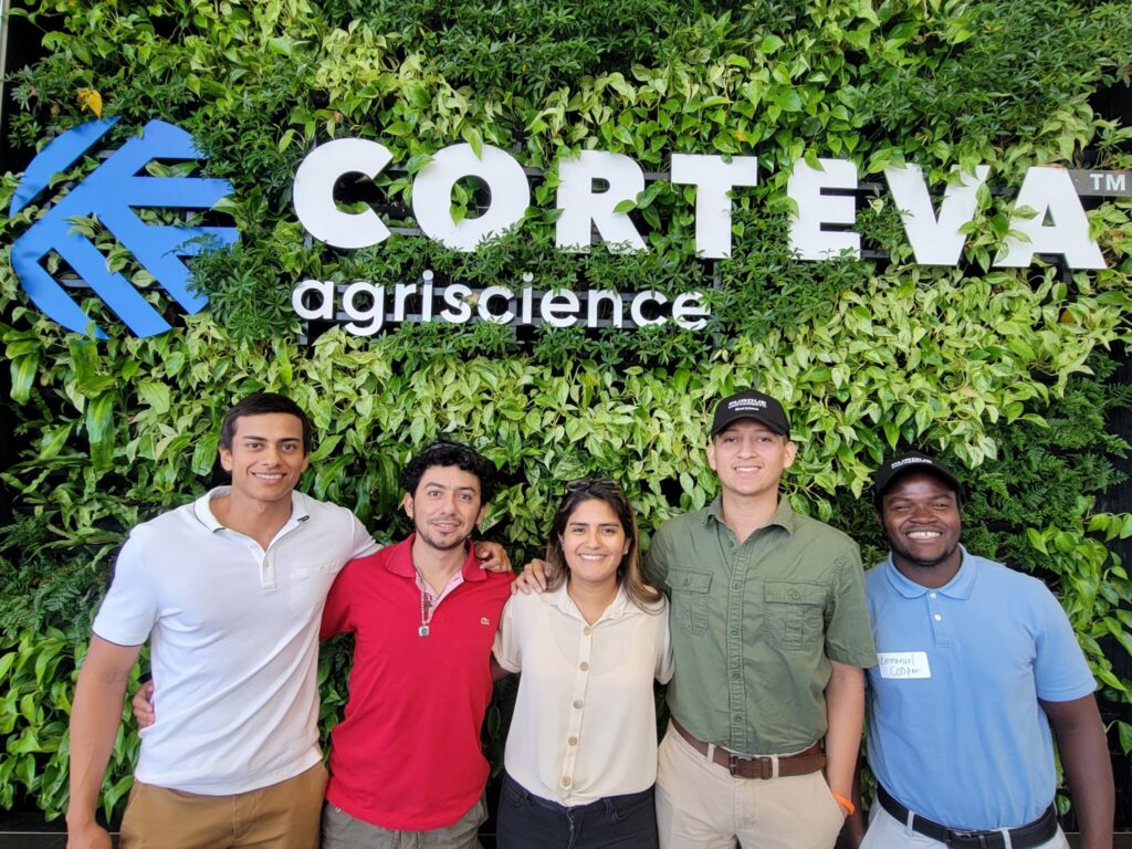Weed Science Team standing in front of green wall with "Corteva Agriscience" sign
