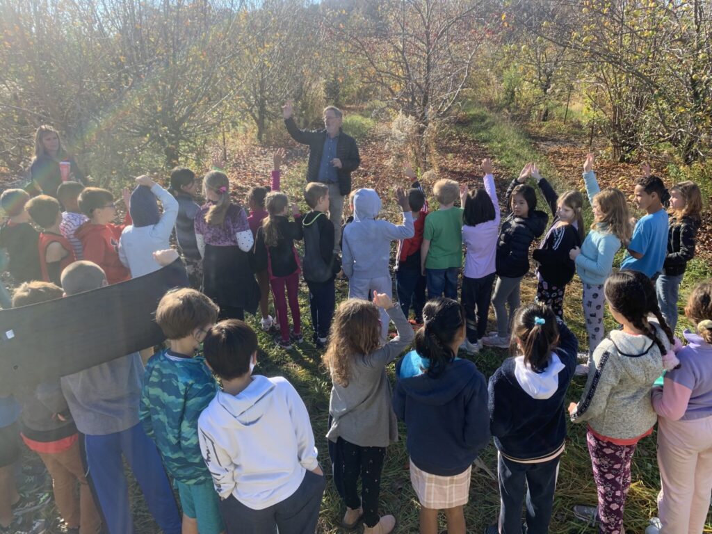 Peter Hirst with a group of third graders in an apple orchard