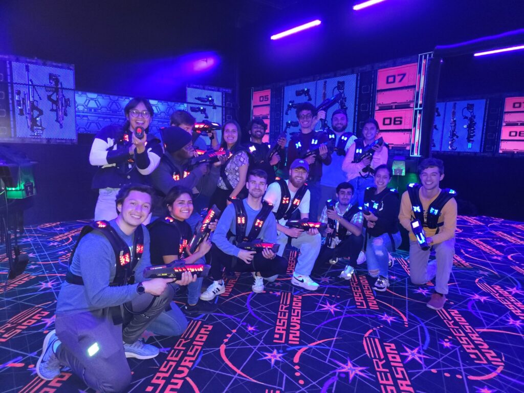A large group of grad students posing for the camera with laser tag gear.