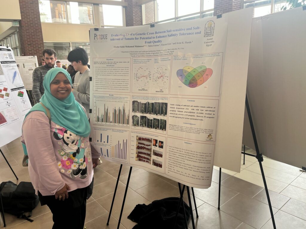 Dhuha Mohamed standing in front of her poster presentation.