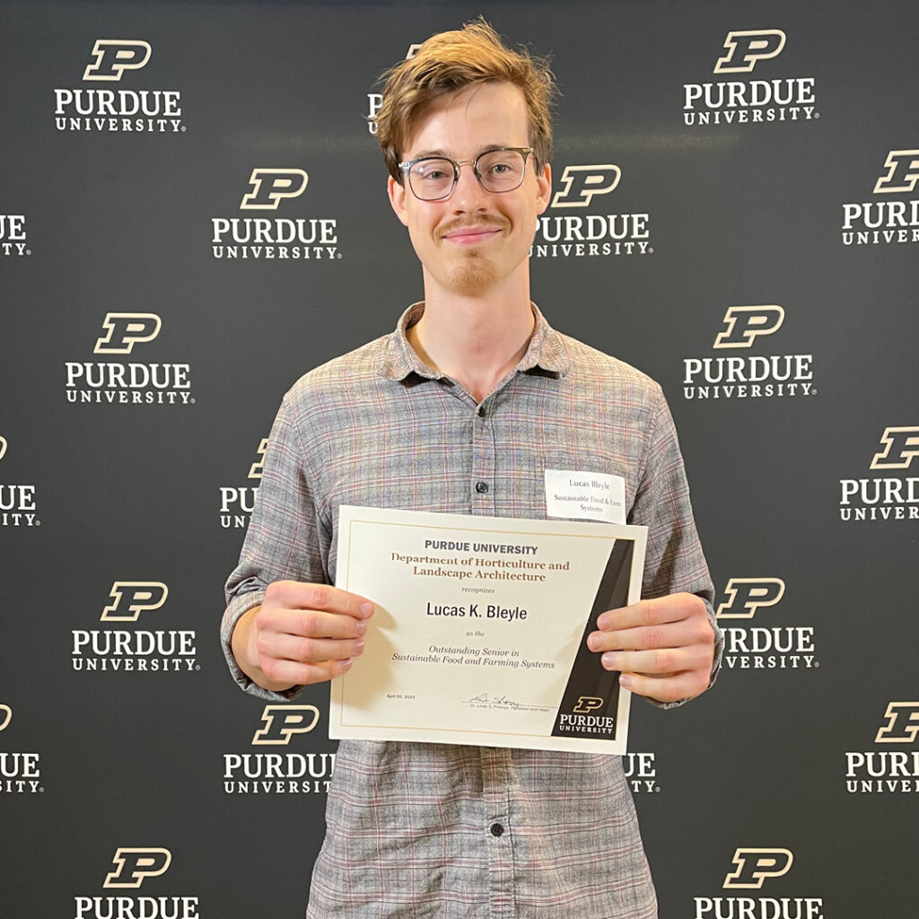 Lucas Bleyle, Outstanding Senior in Sustainable Food and Farming Systems, stands in front of a Purdue University backdrop.