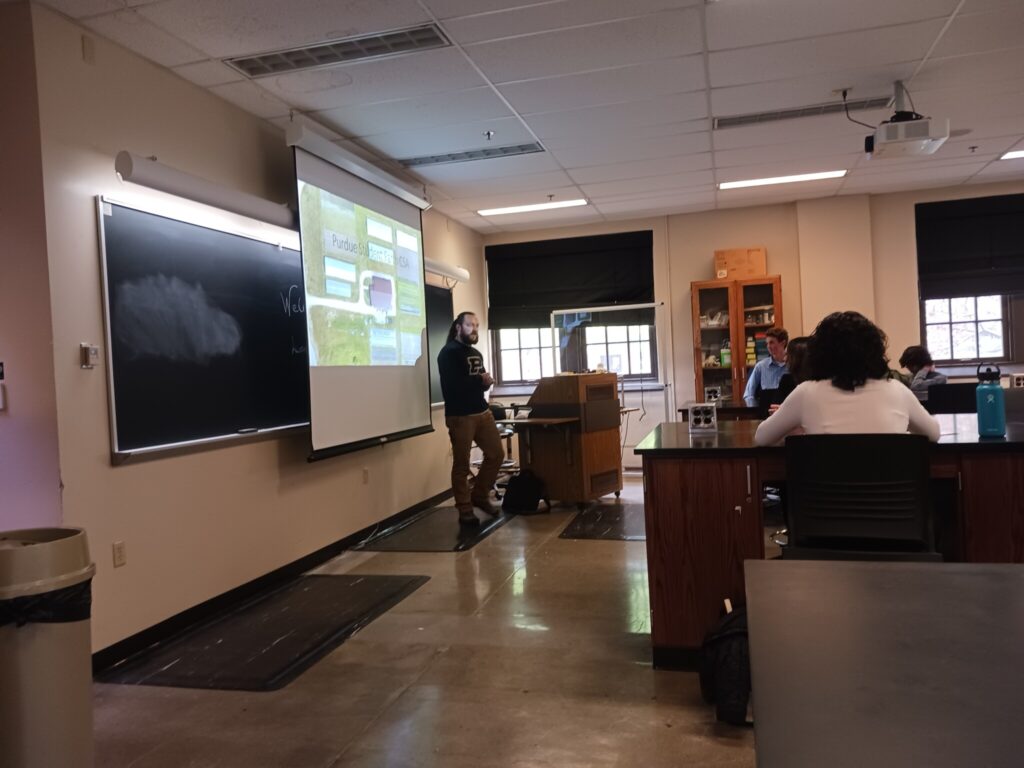 Chris Adair presenting a PowerPoint in front of a laboratory classroom.
