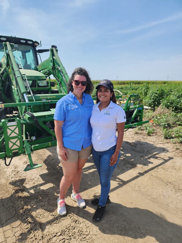 Lauren Lazaro (left), and Jeanine Arana (right) standing in front of an Agronomy Test Machine at Arkansas. 