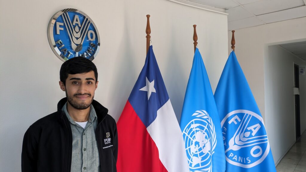 Cristian Salinas standing next to the flags of Chile, the UN, and FAO.