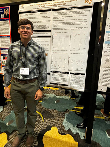 Josue Cerritos standing in front of his research poster.