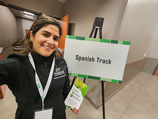 Jeanine Arana standing outside the conference room with the sign "Spanish Track."