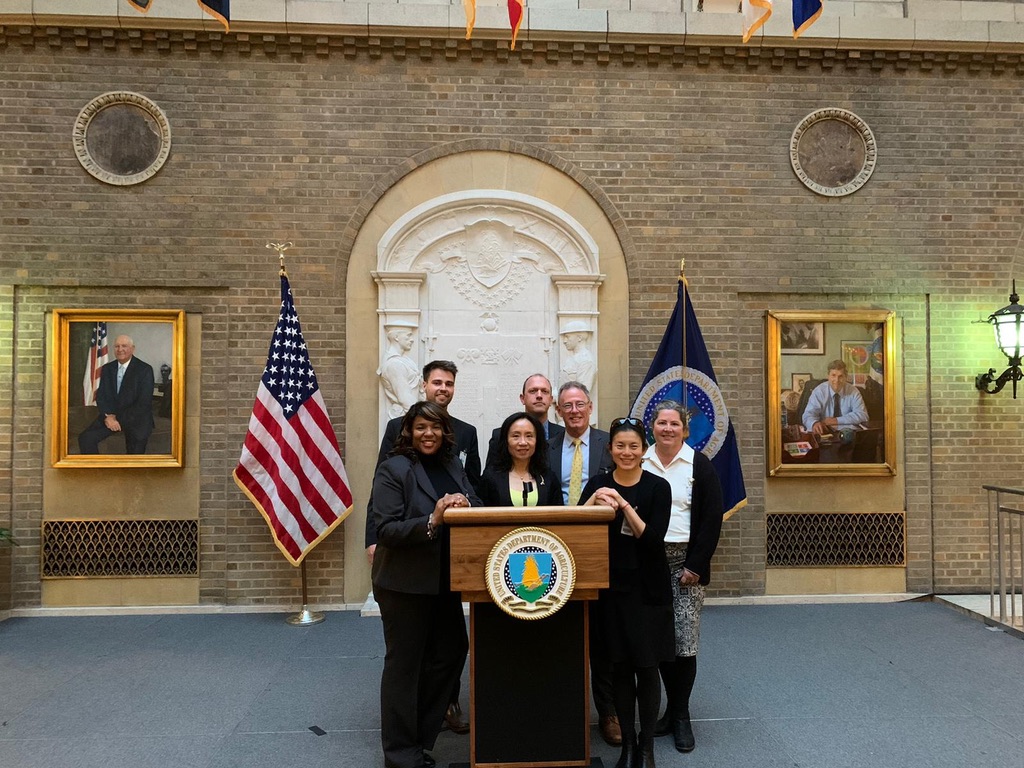 Members of the the International Research Academy standing around the USDA Podium.
