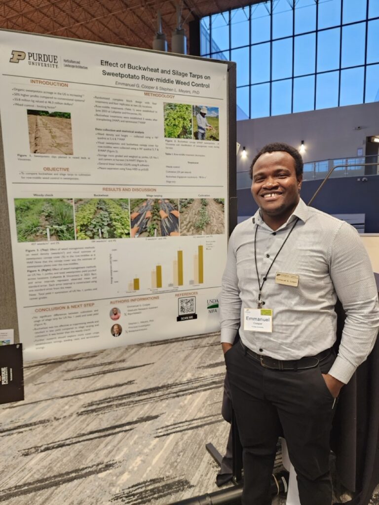 Emmanuel Cooper standing in front of his research poster.