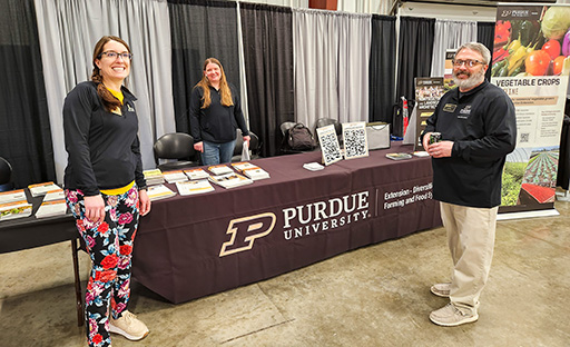 Karen Mitchell, Laura Ingwell, and a gentleman standing near the Purdue Extension DFFS table.