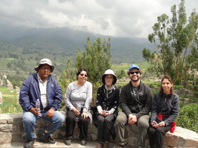 FIve adults sitting with the mountains and landscape behind them.
