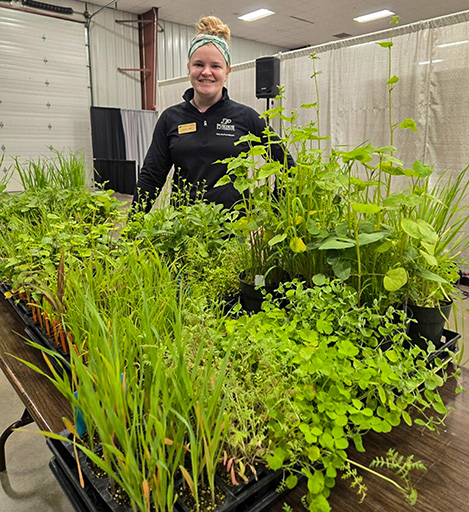 Ashley Adair standing behind a table of cover crop plant specimens.