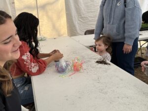 A little girl waits for her plant necklace.